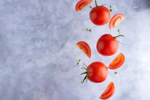 Three fresh red tomatoes with micro grins on a gray background, top view, cop Foto stock