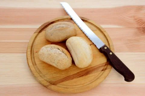 Three fresh rolls with a bread knife Stock Photos