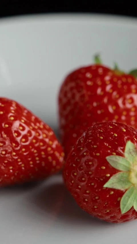 Three fresh strawberries on plate rotating close up Stock Footage 344691960