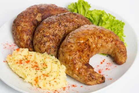 Three fried breaded cutlet with lettuce, mashed potatoes and pepper on white Fotos Stock