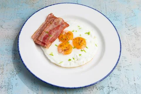 Three fried eggs with bacon in a plate Stock Photos