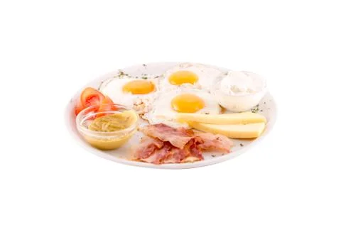 Three fried eggs garnished with cheese, ham and tomatoes Stock Photos