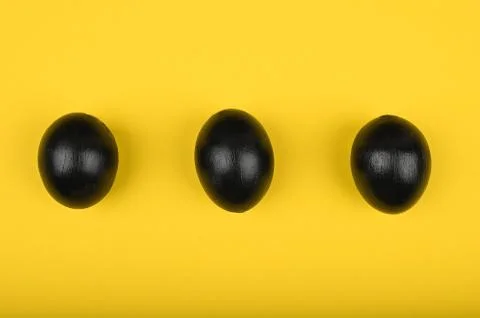Three fried eggs on a yellow background. flat lay. Black Easter. three black  Foto stock