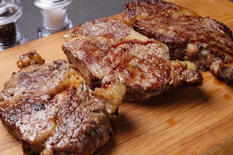 Three fried marbled beef steaks on a cutting board, close-up Stock Photos