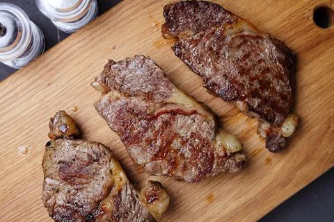 Three fried marbled beef steaks on a cutting board, close-up, top view Foto stock