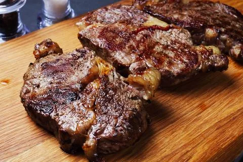 Three fried marbled beef steaks on a cutting board Stock Photos
