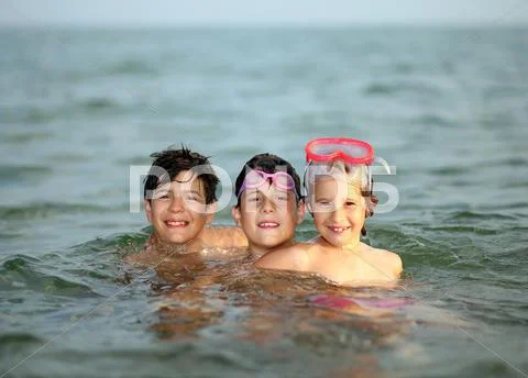Three friendly brothers swimming in the sea during summer vacation Stock Photos