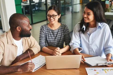 Three friendly office colleagues talking to each other at work Stock Photos