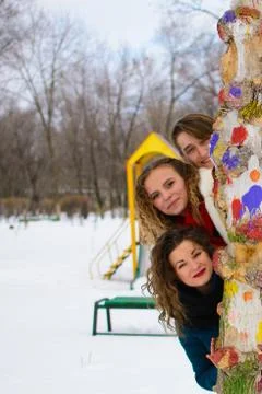 Three friends are posing in winter at a tree Stock-Fotos