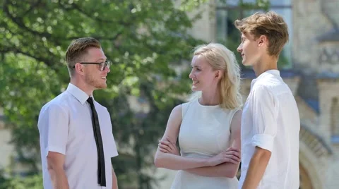 Three Friends Are Talking Smiling Gesticulating Courtyard of Old Building Park 動画素材 64813099