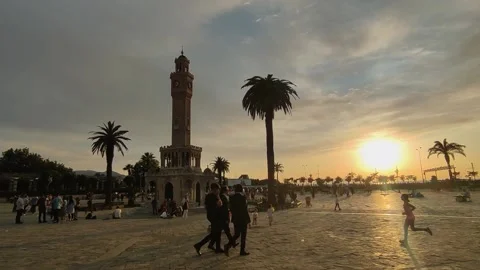 Three friends are  walking in front of the İzmir clock tower on a cloudy sunset Stock Footage 195222485