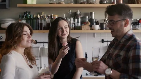 Three friends is clinking glasses and drink wine on a home kitchen party Stock Footage 73590577