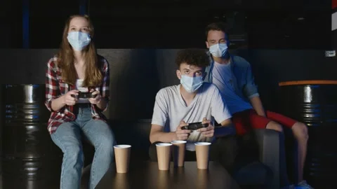 Three friends with face masks in front of the screen are playing together in the Video stock 136374013
