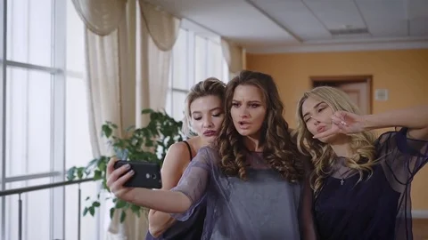 Three friends fool around in front of the camera, showing a fashionable pose to Stock Footage