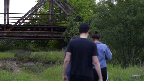 Three friends going for a railroad bridge in wilderness in slow motion Video stock 134014956
