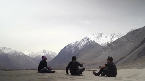 Three friends having a conversation while sitting on the ground in the mounta Stock Footage 153512288