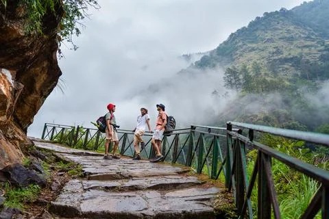 Three friends hiking on a stone path with metal railing near Madhyamaheshwa.. Stock Photos