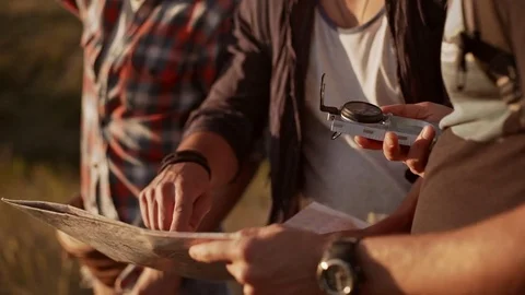 Three friends with map and compass trying to find way in prairie. Close up view Stock Footage 71455641