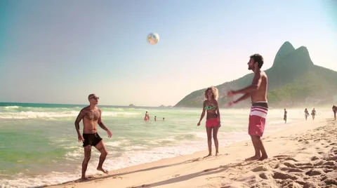 Three friends playing football on Ipanema beach Stock Footage 59376792