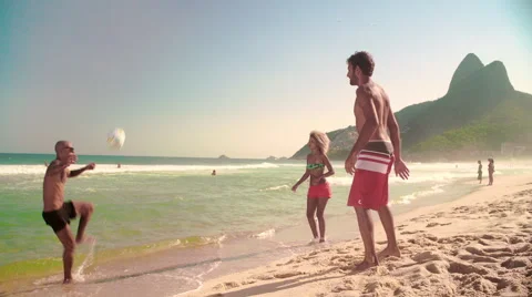 Three friends playing football on Ipanema beach Stock Footage 59376933