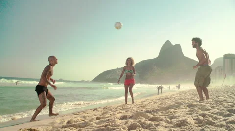 Three friends playing football on Ipanema beach Stock Footage 59377167