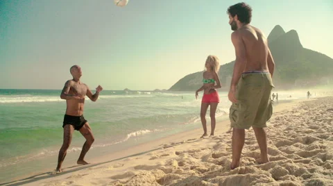 Three friends playing football on Ipanema beach Stock Footage 59377168