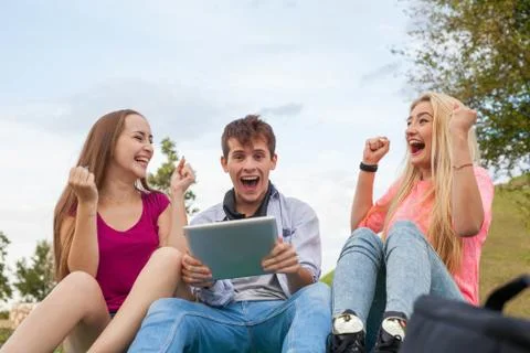 Three friends playing game on tablet pc. They winning again. Stock Photos
