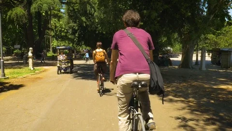Three Friends Riding Bycicles in a Park in Rome Stock-Footage 77457209