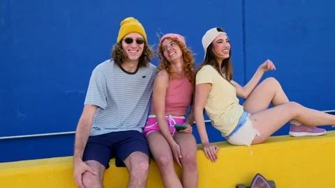 Three friends sharing laughter on a colorful urban street Stock Footage 309984495