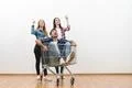 The three friends with a shopping cart gesture on a white wall background Photo
