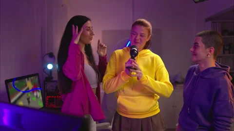 Three friends singing together into a microphone in a fun Vídeos de archivo 326223339