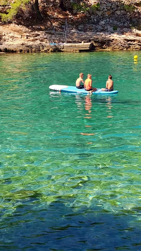 Three friends sit and talk on a SUP board Stock Footage 315666716