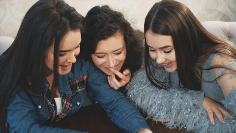 Three friends sitting in a cafe with a smart phone and having a funny Stock Footage 114000970
