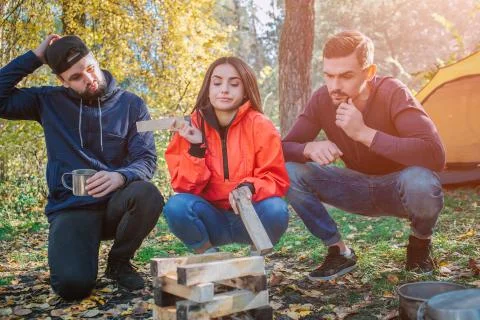 Three friends sitting in squad position and look at brickets of wood. Young Фото