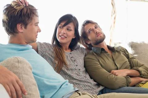Three friends sitting together on a couch Stock Photos