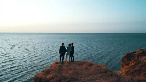 The three friends standing on the mountain edge against the seascape Stock Footage 156388898