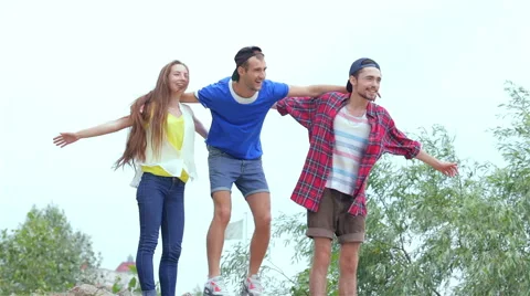 Three friends standing on the rocks at the river and flap their hands Stock Footage 40607820