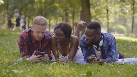 Three friends using phone in park Stock Footage 114832754