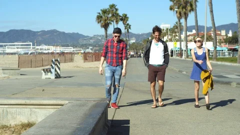 Three friends walking on a beach bikepath Stock Footage 86537496