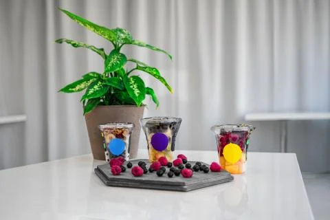 Three fruit smoothies on a white table, and assorted ingredients, blueberries Stock Photos
