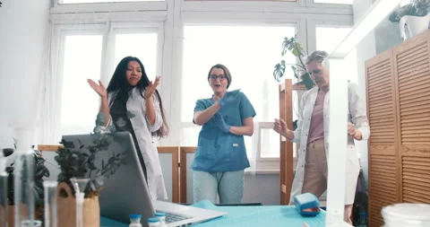Three fun excited young and senior happy female doctors dance celebrating Vidéo 150973676