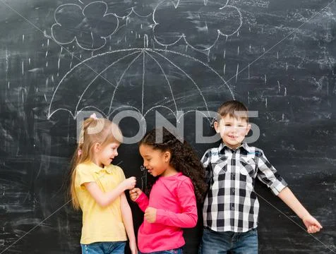 Three funny children with umbrella drawn on the blackboard Stock Photos
