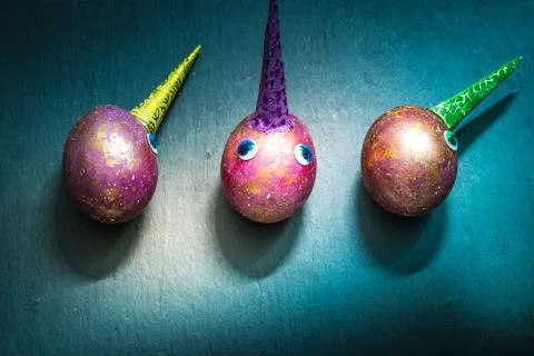 Three funny unicorn space easter eggs on slate board. Top view. Stock Photos