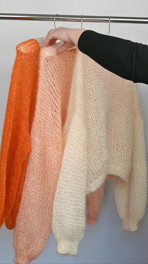 Three fuzzy mohair sweaters hanging. Stock Footage 334747784