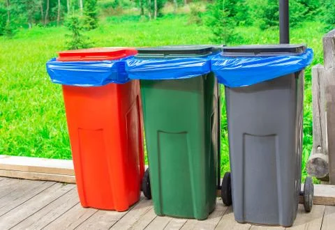 Three garbage cans with blue plastic bags Stock Photos