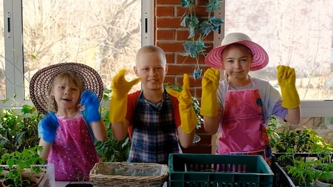 Three gardener children in multi-colored protective gloves on the veranda. 库存影片 128350653