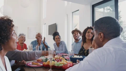 Three generation black family sitting at dinner table celebrating together, Stock Footage