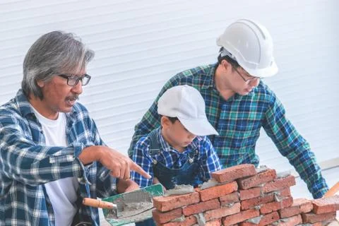 Three generation of builders is helping to build brick wall for togetherness  Фото