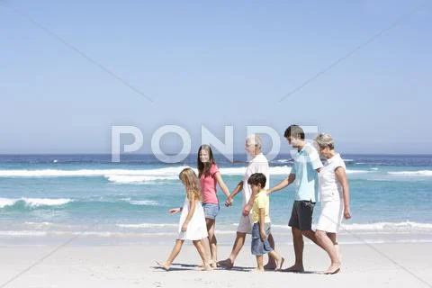 Three Generation Family Walking Along Sandy Beach Stock Photos