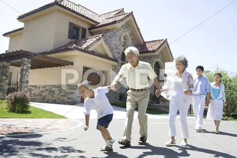 Three generation family walking by a house Stock Photos